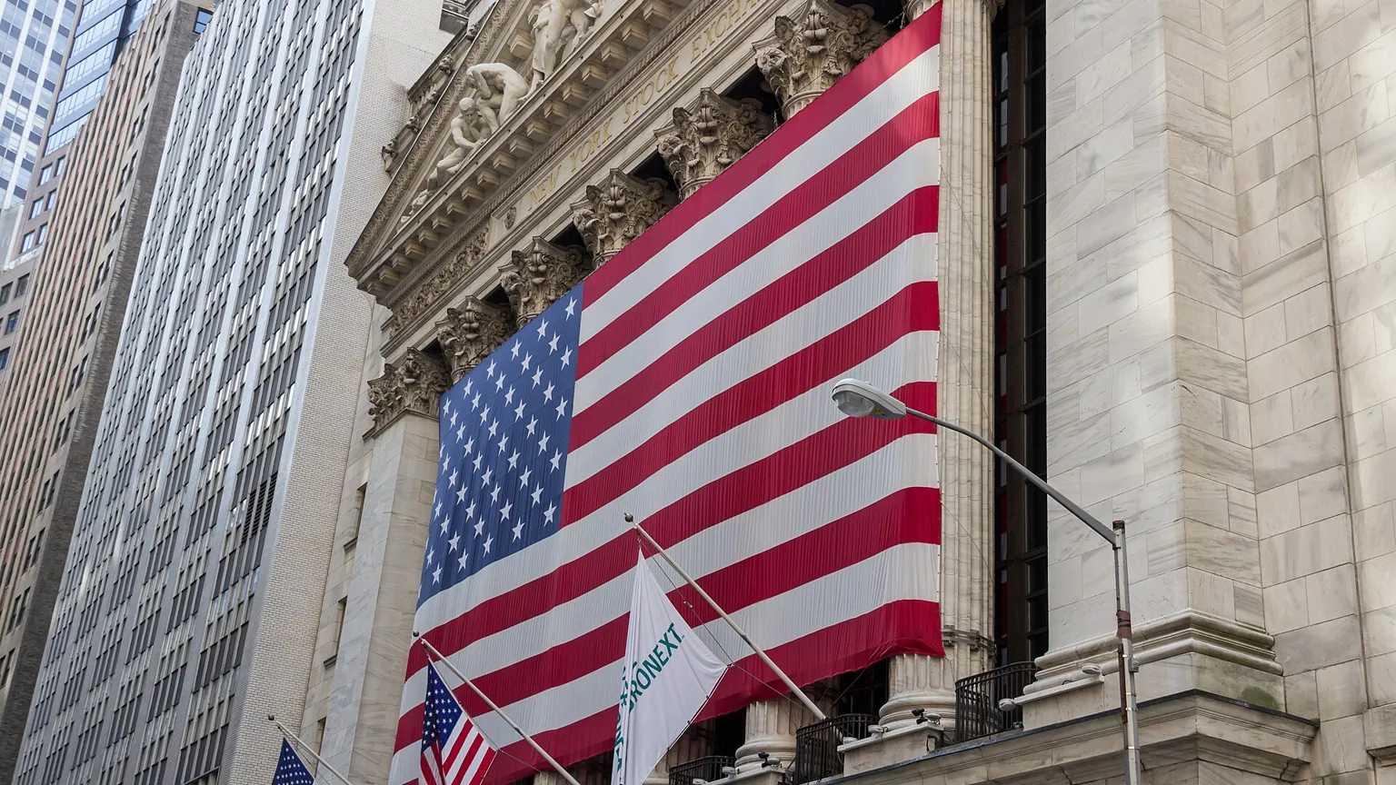 Facade of the New York Stock Exchange with a large US flag